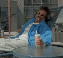 A man in sunglasses lounging on a deck chair with a drink